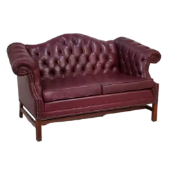 Maroon leather chesterfield loveseat with button tufted back. Side view.