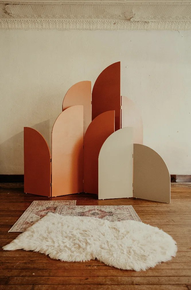 Ezra backdrop with rug and throw WEBP Full view of arched panel backdrop. Rugs and sheepskin throw in front