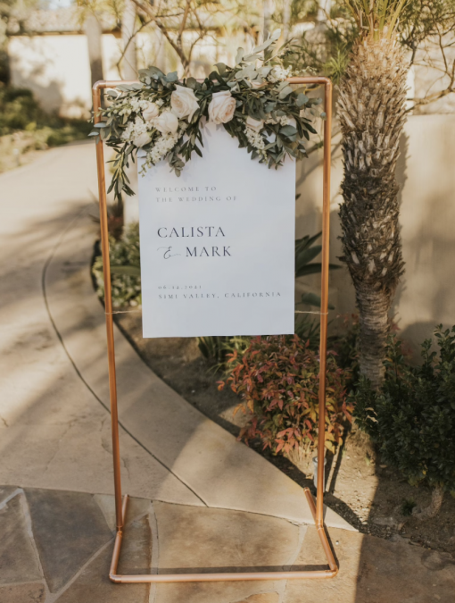 Tall copper stand used to hang a welcome to the wedding sign.