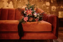 Rust colored mid-century modern velvet sofa with florals from a wedding.