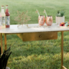 Display table with white marble and gold legs holding various items outside.