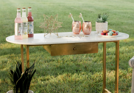 Display table with white marble and gold legs holding various items outside.