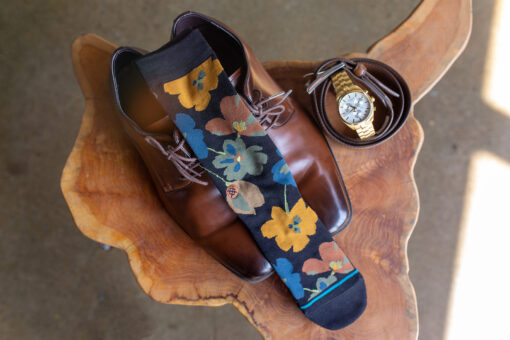 Wooden side table arial view with items from the groom - socks, watch, shoes, etc.