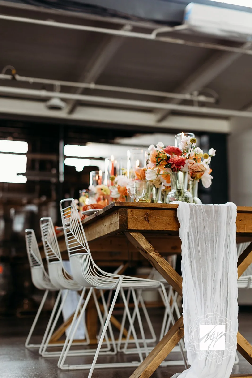 Wedding styled shoot with white chairs and farm table rental WEBP Wedding reception setup with farmtable and white wire chairs. White drape on the table with florals.