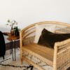 Overside wicker rattan chair with pillows sitting on a black and white rug. White walls in background.