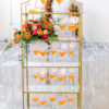 Gold framed bookshelf with orange liquid in wine glasses as a welcome drink to a wedding reception