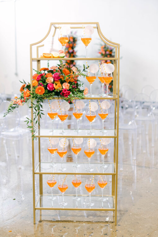 Gold framed bookshelf with orange liquid in wine glasses as a welcome drink to a wedding reception