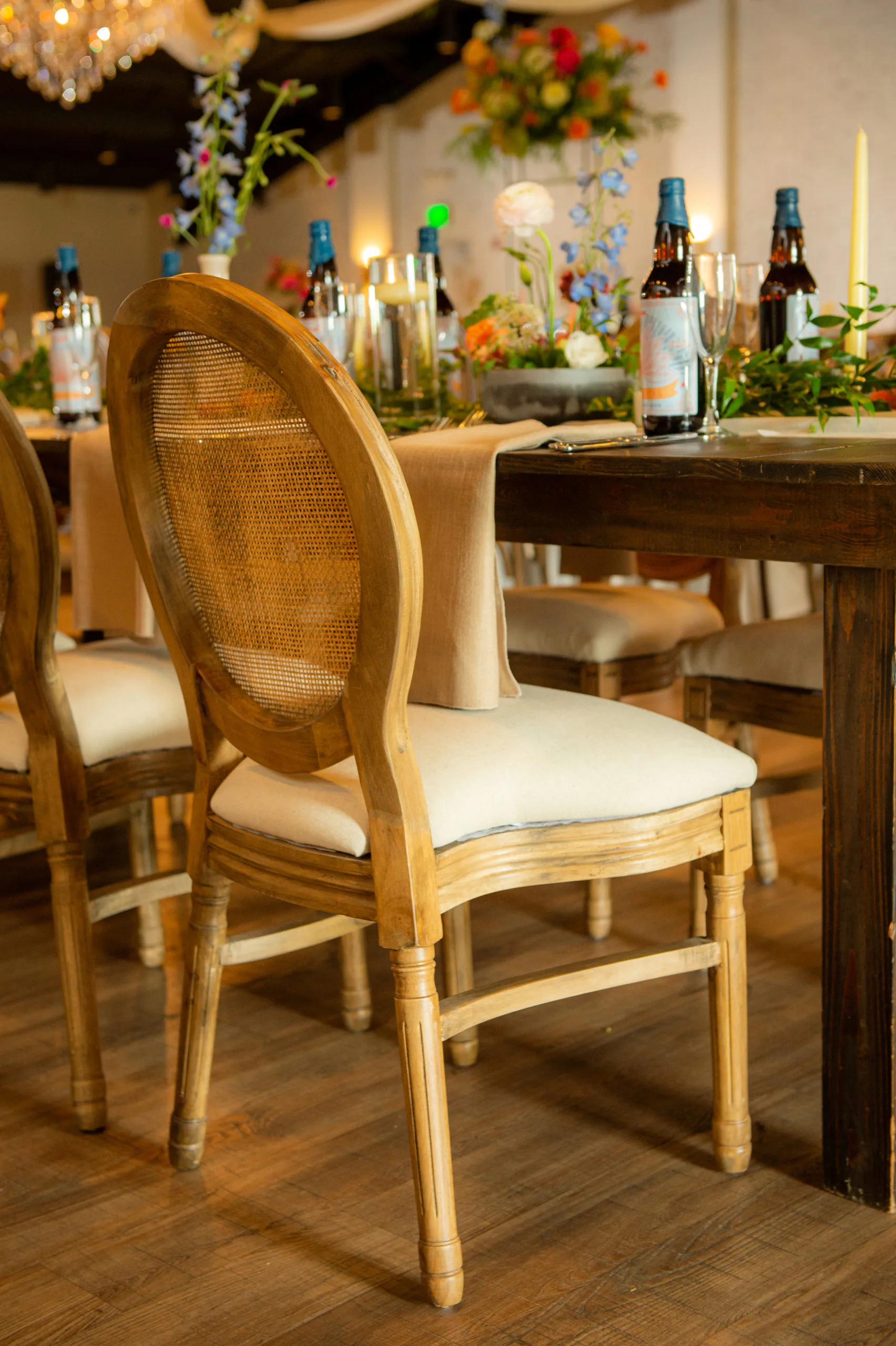 Wedding reception featuring louis chairs WEBP Full back angle view of our Louis Cane Back Chair rental from Violet Vintage Rentals with cushion as used at a wedding reception at a winery
