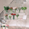 White display cart holding vases of flowers with stairs in the background