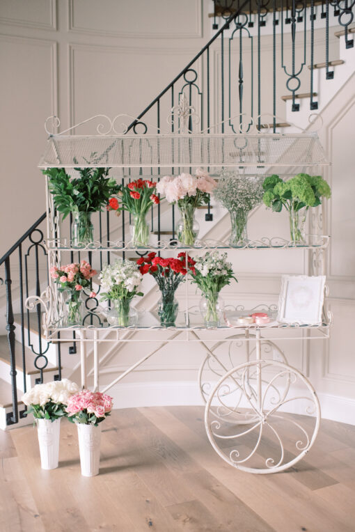 White display cart holding vases of flowers with stairs in the background