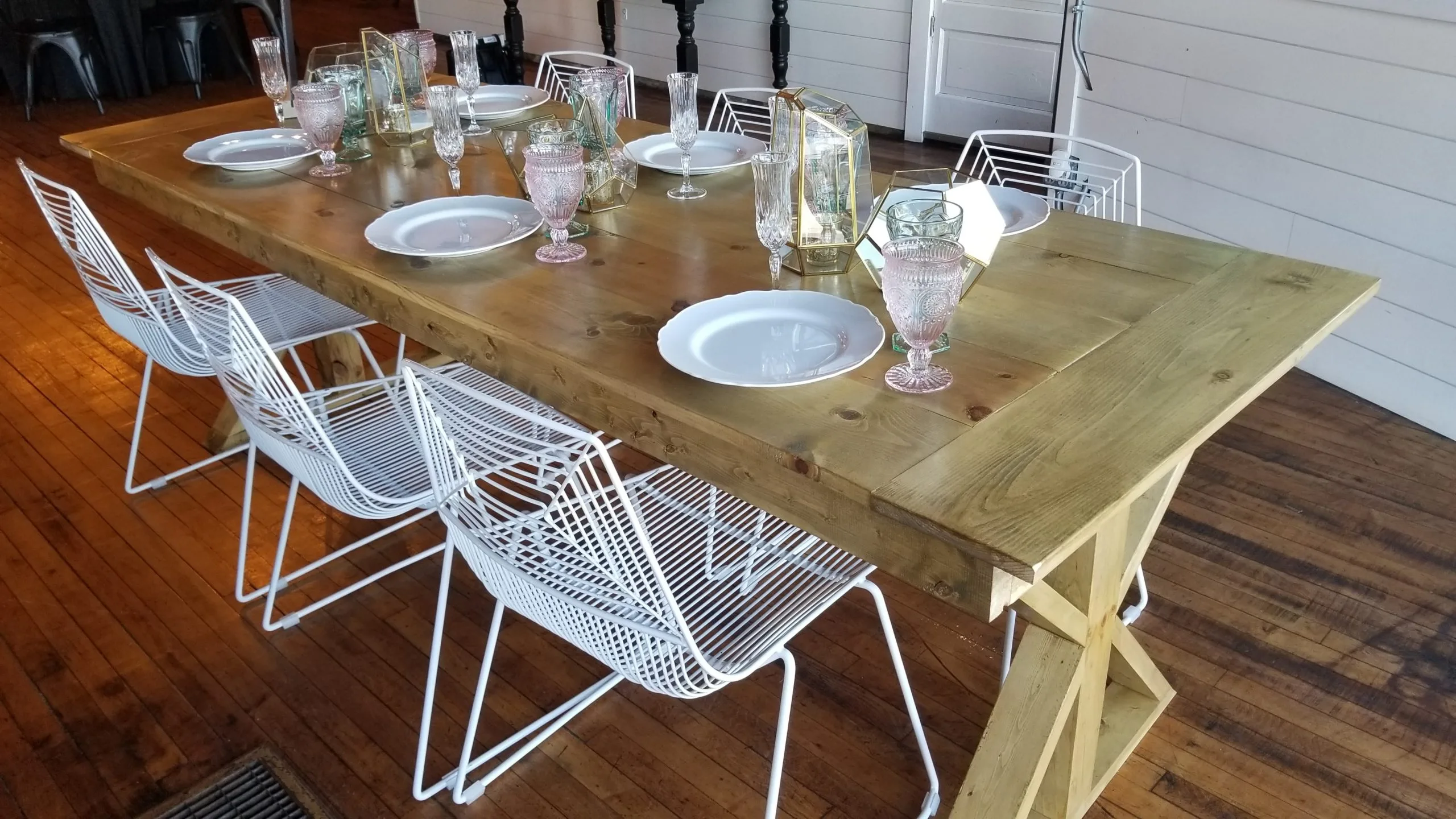 White wire chairs with Charleston Table at 5 East by Hali Mae. WEBP 6 White wire modern chairs around a solid wood farm table