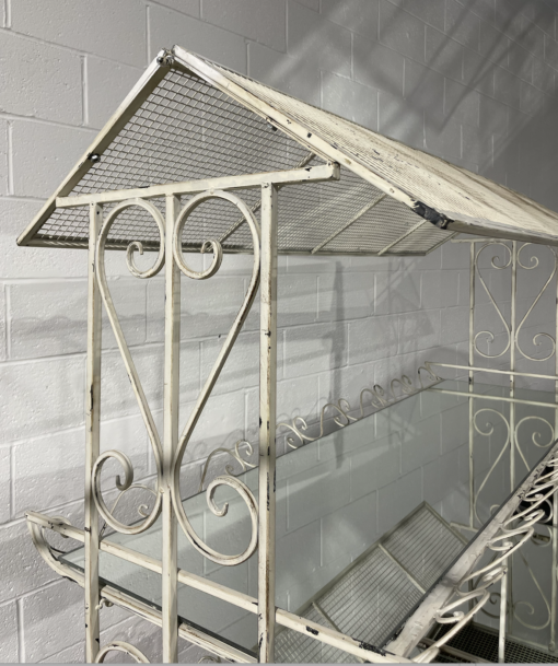 Close up on side of display cart showing antique white paint with ornate metal design