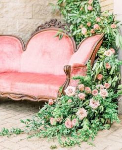 Angle view of the loveseat with heavy green and pink florals draping the back and down the side
