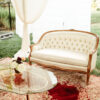 Intimate lounge area with a cream settee, red rug, and glass top coffee table