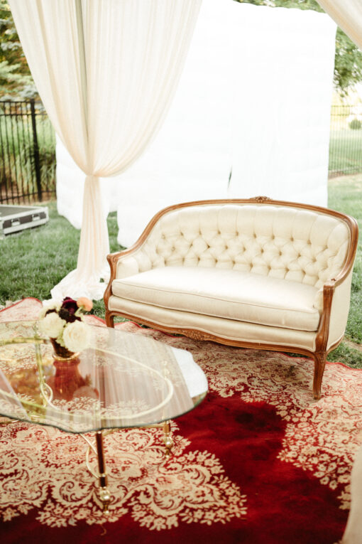 Intimate lounge area with a cream settee, red rug, and glass top coffee table