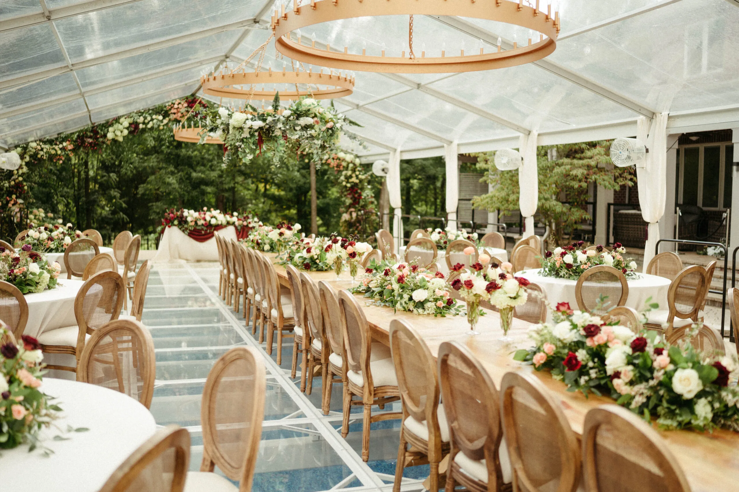 eric-veronica-wedding-brynnaisabell(41of859) WEBP Wedding reception with a clear tent, a long row of farm tables and high end Louis chairs. Circular lighting strung from the ceiling