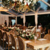 Solid wood farm tables with matching Louis chairs under a clear tent at wedding reception in Noblesville, Indiana