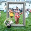 Giant free standing frame with a black woman posing in the center. On grass outside of the Lilly house at Newfields