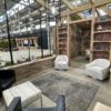 Expo event seating area with two swivel gray barrel chairs, gray rug, and black arm chairs under a wooden room structure