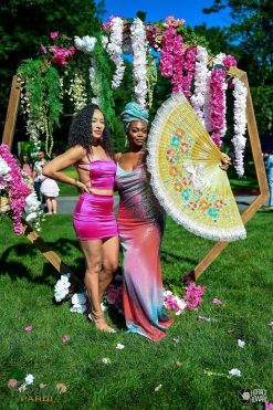 Custom wooden octagon wedding arch rental decorated with pink and white florals for a sunny outdoor wedding in downtown Indianapolis, featuring guests posing in formal attire.