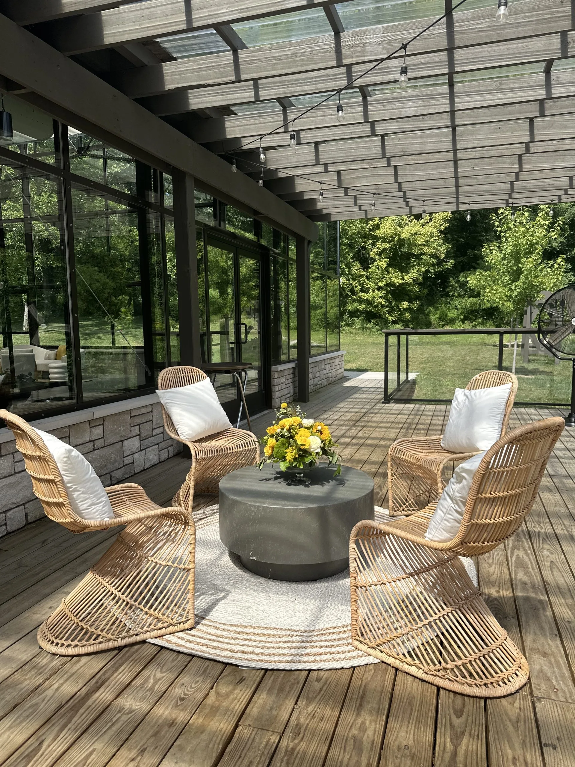 rattan cruved chair rental WEBP Four rattan light colored cruved chairs around a gray coffee table on a round rug