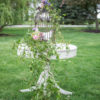 Round table used to hold doves at wedding. Greenery draping table. Outside on grass at a styled shoot