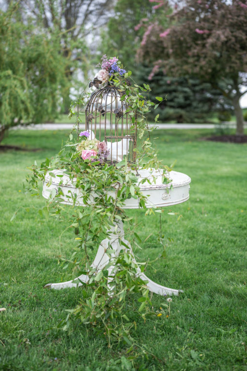 Round table used to hold doves at wedding. Greenery draping table. Outside on grass at a styled shoot