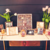 Vintage gold frames with photos sitting on marble top gold desk. Tulips in vases against a dark gray wall