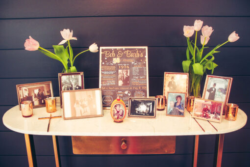 Vintage gold frames with photos sitting on marble top gold desk. Tulips in vases against a dark gray wall