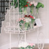 Elegant white display cart with two tiers holding flowers.