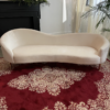 White velvet curved sofa with a bold red rug and elegant design pattern.