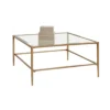 Large square coffee table with muted gold edges, legs and a glass top.