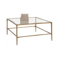 Large square coffee table with muted gold edges, legs and a glass top.