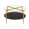 Modern round coffee table with glass top, gold legs that form an X on the top, and a black bottom shelf