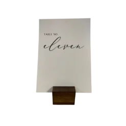 Small dark wood place card holder holding a piece of thick paper with a table number printed on it