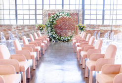 Pink arm chairs used in wedding ceremony. Windows and brick wall in the background.