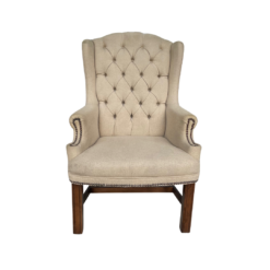 Tan high back wing chair with button tufting and nail head trim on arms. Dark wood legs.
