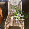 Light brown rattan chair with florals on a polished concrete floor.