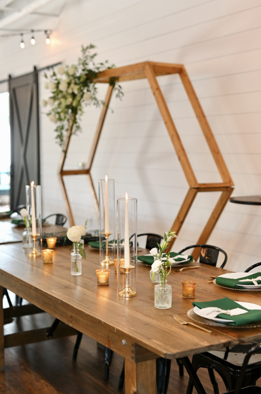 Wedding head table with backdrop behind. Tablesetting with white, deep green and gold votives.