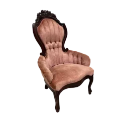 Victorian arm chair with pink velet, channel tufted back, dark wood ornate trim and rolled arms.
