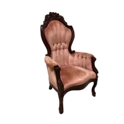 Pink velvet victorian arm chair with channel tufts and ornate wood frame.