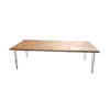 Wooden farm table with medium stain. Black metal hairpin legs on each corner.