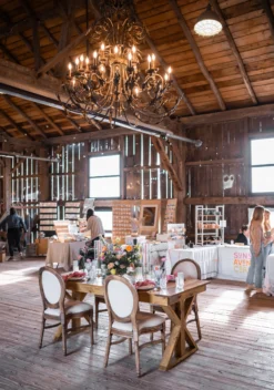 Wooden farm table with 4 french Louis chairs at a quaint barn setting.