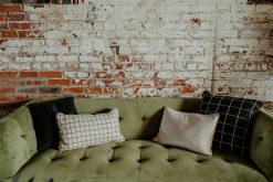 Green velvet modern sofa close up with a range of square and rectangle white and black pillows.