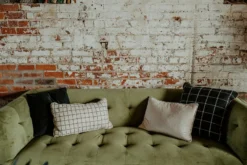 Green velvet modern sofa close up with a range of square and rectangle white and black pillows.