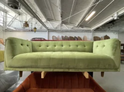 Pear green velvet sofa on a rack in an industrial warehouse