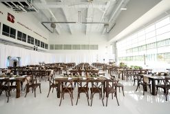 dark vineyard crossback chairs and dark wooden farm tables in an airport hangar turned into wedding reception
