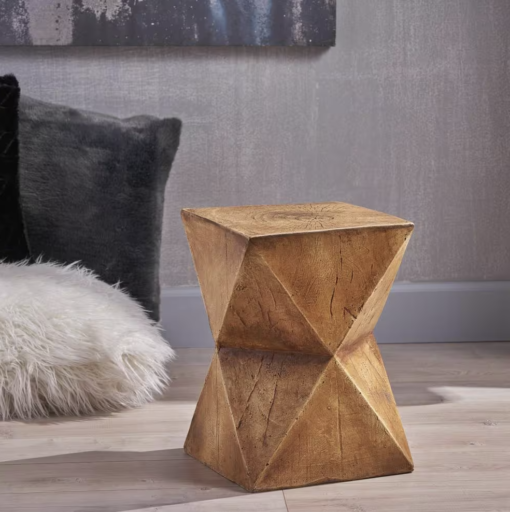 Accent table with large pillows in the background and a gray wall.