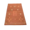 Rust colored rug with geometric diamond shaped designs in white, yellow and orange.