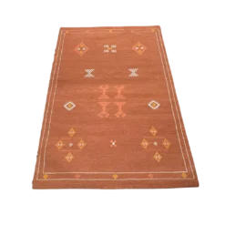 Rust colored rug with geometric diamond shaped designs in white, yellow and orange.